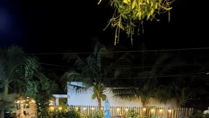 A nighttime outdoor area with a mosaic-tiled pathway, potted plants, and a decorative fence. - Doi Dua Homestay (Mui Ne)