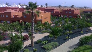 Zona residencial con varias edificaciones de techo rojo, palmeras y un sendero pavimentado.