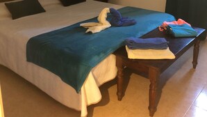 Un dormitorio con una cama, una mesita de noche, una mesa y dos cuadros colgados en la pared.