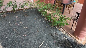 Un patio con mesa y sillas, rodeado de plantas y una pared decorada con un cuadro.