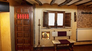 A rustic room with a wooden cabinet, a bench, a window with shutters, and a stone wall. - La Casa de Lucas (Clavijo)