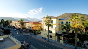 A street view with buildings, palm trees, and mountains in the background. - Fornaci 9 - 2-4 people 100 meters from the sea (Pietra Ligure)