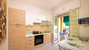 A modern kitchen with wooden cabinets, a built-in microwave, and a gas stove. - Fornaci 9 - 2-4 people 100 meters from the sea (Pietra Ligure)