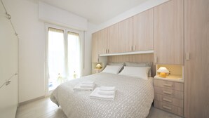 A bedroom with a bed, bedside tables, a wardrobe, and a window. - Fornaci 9 - 2-4 people 100 meters from the sea (Pietra Ligure)