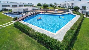 Een buitenzwembad, ligstoelen bij het zwembad