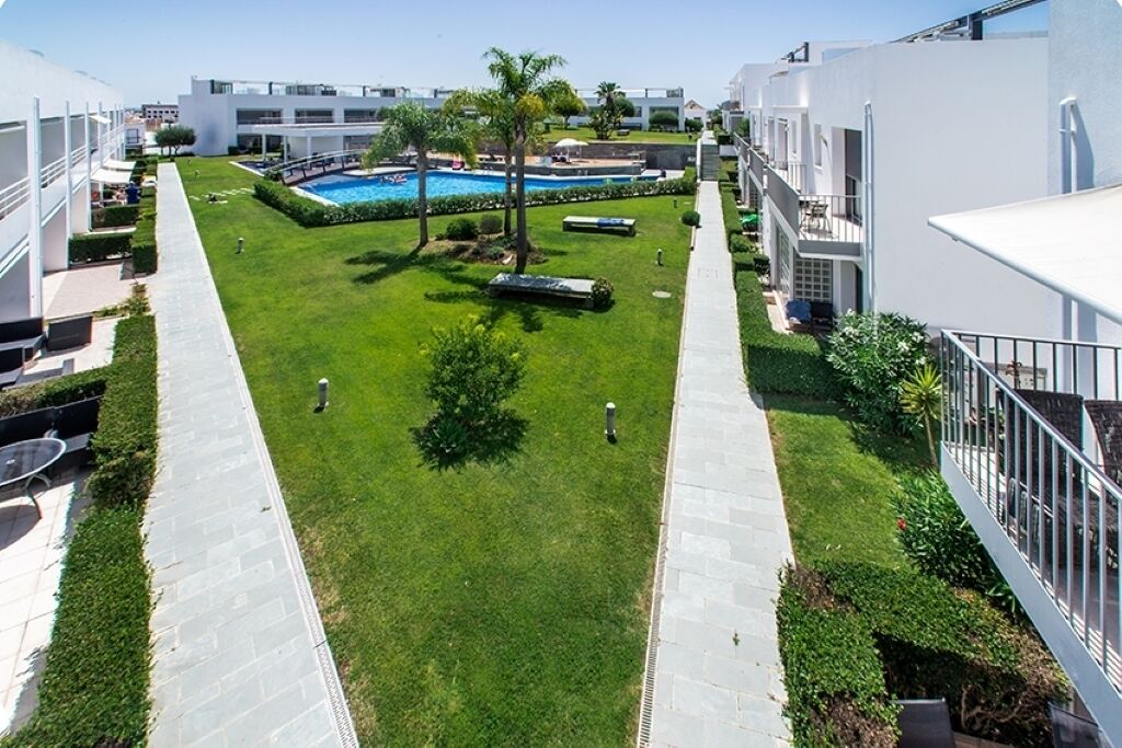 A courtyard with a swimming pool, surrounded by modern buildings with balconies.