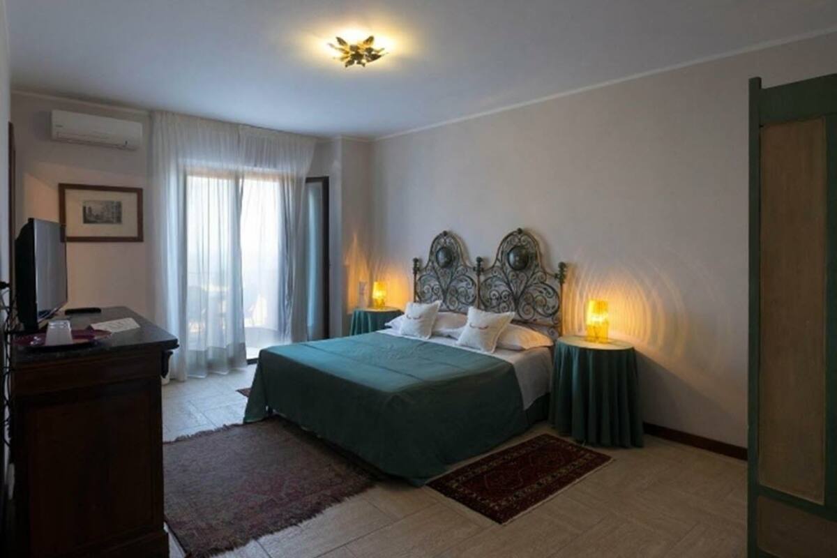 A bedroom with a bed, bedside tables, a desk, and a television.