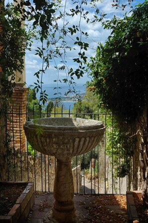 A stone fountain in a garden with a view of the sea. - Casa Mathea (Castelmola)