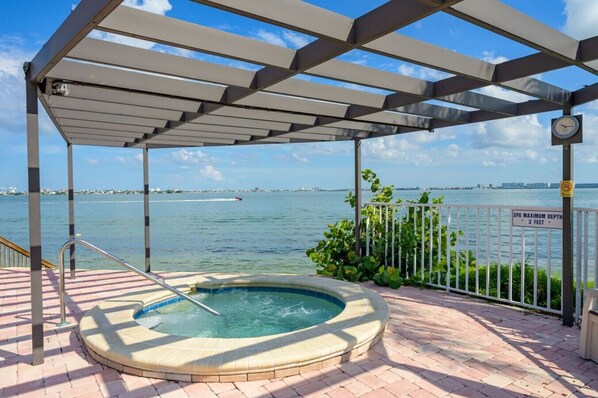 A hot tub under a pergola with a view of the water and a sign indicating a maximum depth of 3 feet.