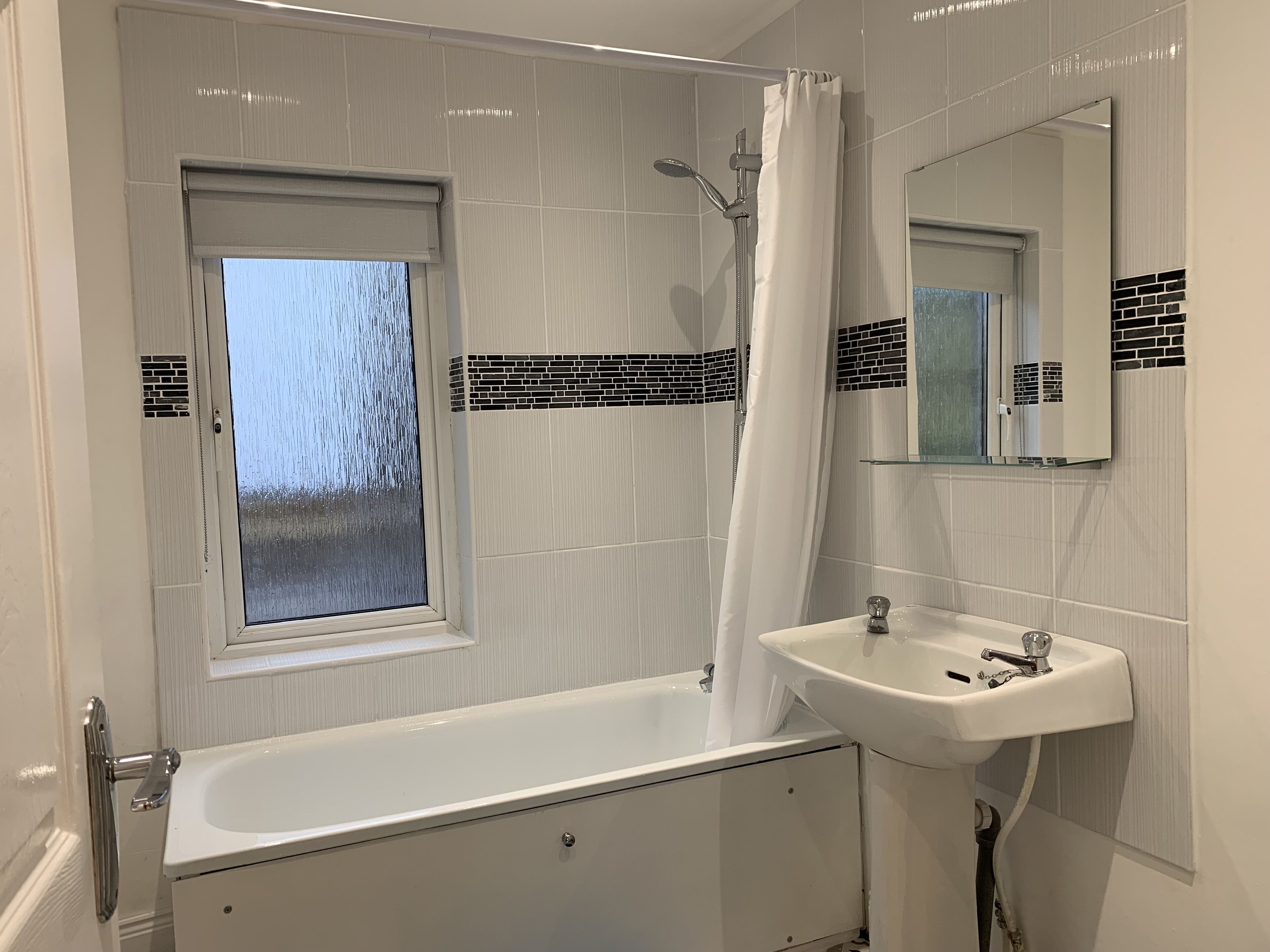 A modern bathroom with a bathtub, a window, a shower, and a sink.