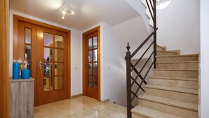 Una escalera con barandilla de madera y escalones de mármol color beige.