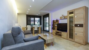 Una sala de estar moderna con un sofá gris, un aparador de madera y un televisor.