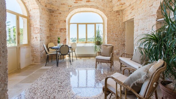 Una habitación rústica con paredes de piedra, una zona de comedor y un amplio ventanal.