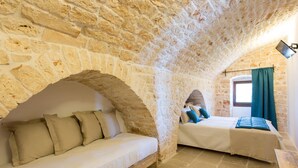 Una habitación acogedora con pared de piedra, una cama, un sofá y un banco de madera.