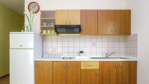Une cuisine avec des meubles de rangement en bois, un réfrigérateur blanc, une horloge et un évier.