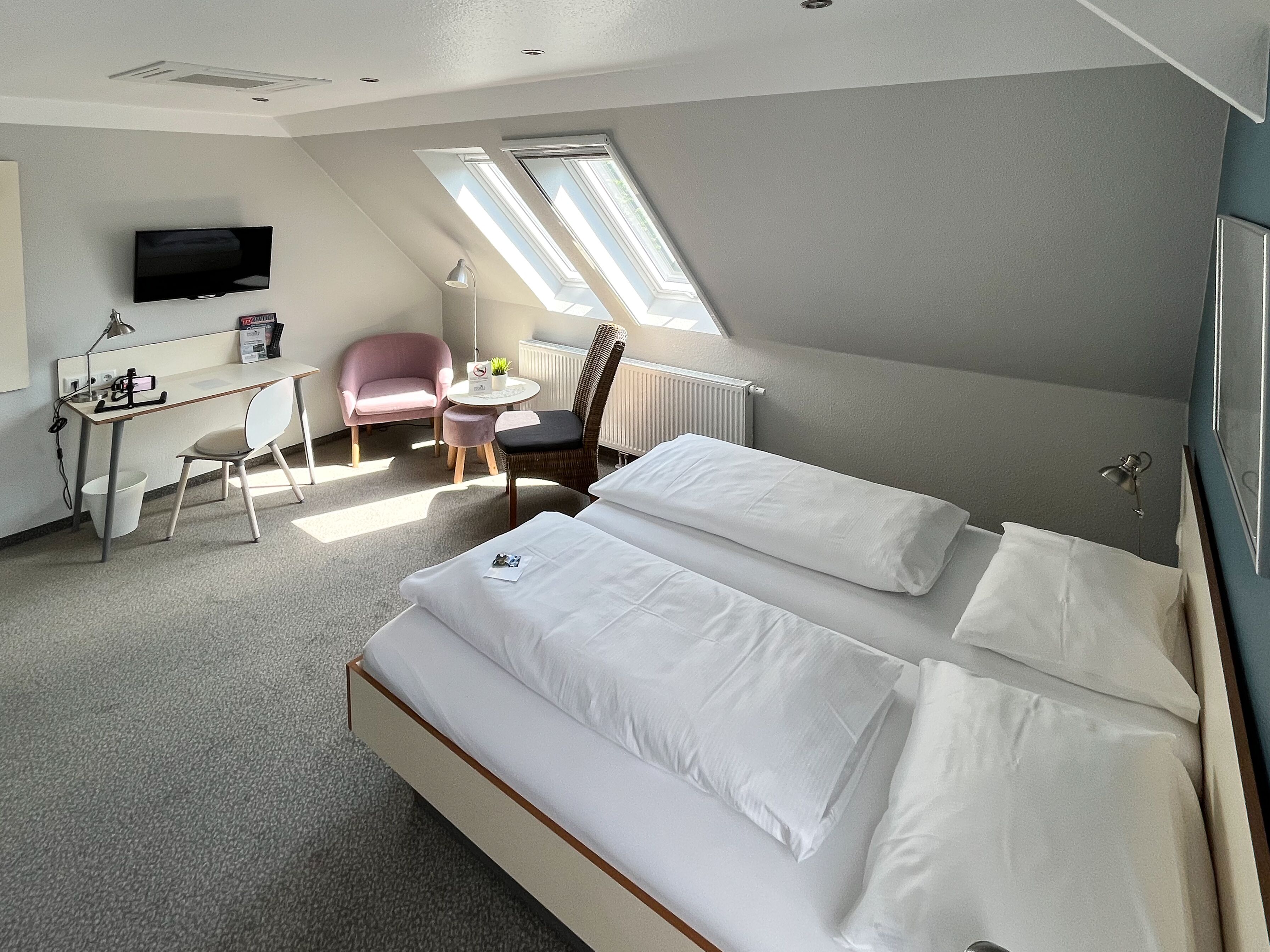 Ein Hotelzimmer mit einem Bett, einem Schreibtisch, einem Sessel, einem kleinen Tisch und einem Fernseher.