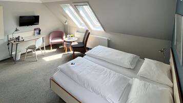 Ein Hotelzimmer mit einem Bett, einem Schreibtisch, einem Sessel, einem kleinen Tisch und einem Fernseher.