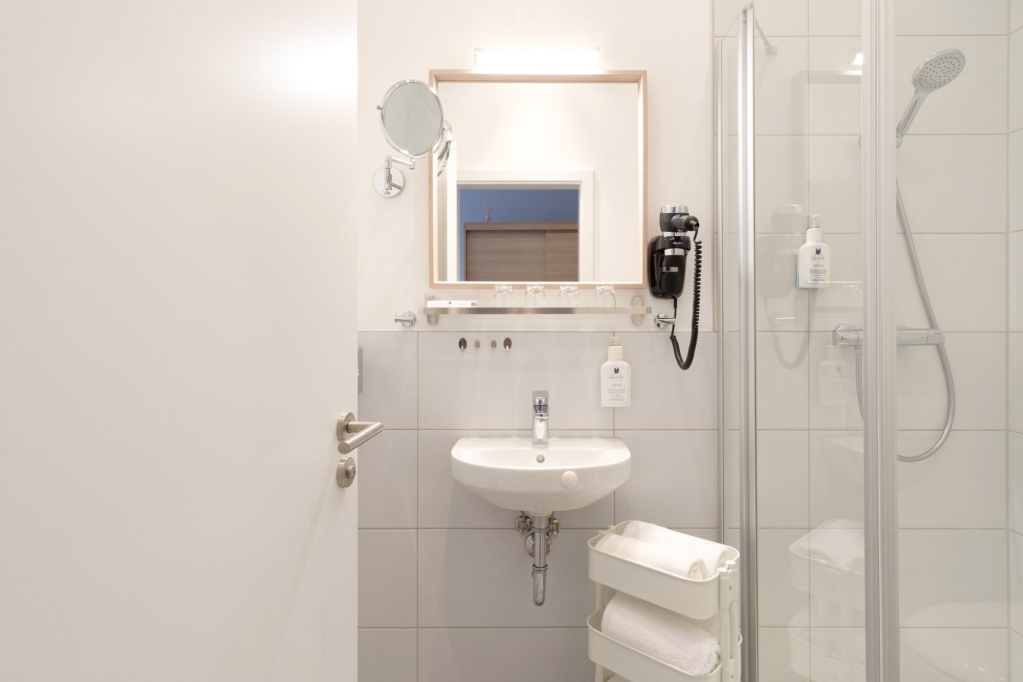 A modern bathroom with a sink, mirror, and shower.