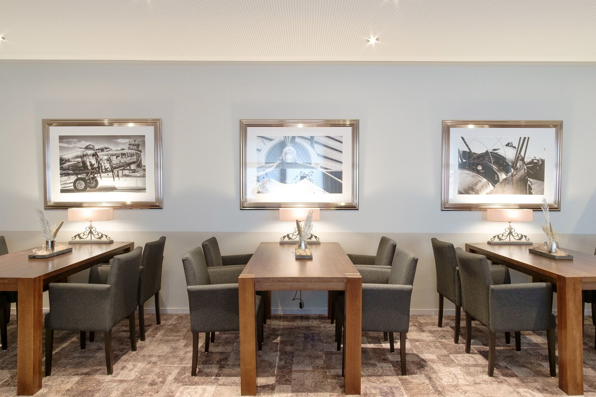 A conference room with three tables, each with a framed photograph above.