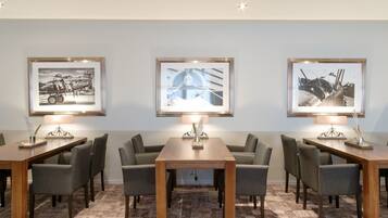 A conference room with three tables, each with a framed photograph above.