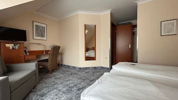Et hotelværelse med en seng, et skrivebord, en stol, et fjernsyn og et spejl.