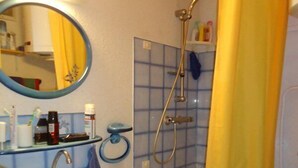 A bathroom with a sink, mirror, shower, and toilet.