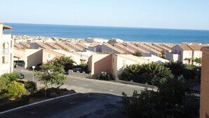 A coastal residential area with rows of terraced houses, a clear view of the sea, and a road in the foreground.