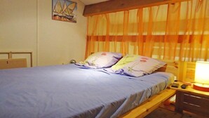 A single bed with a wooden frame, a blue mattress, and floral pillows.