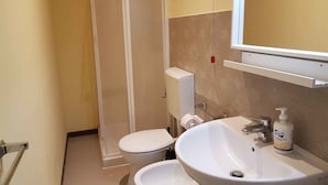 Une salle de bain équipée de toilettes, d’un bidet et d’un lavabo.