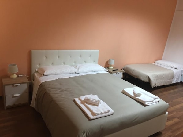 A hotel room with a large bed, two bedside tables, and a smaller bed in the corner.