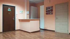 Un espace d’accueil doté d’un plancher en bois, d’un comptoir de réception, d’une porte avec un panneau indiquant la sortie de secours et d’un téléphone fixé au mur.
