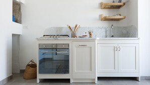 Una cocina moderna con armarios blancos, horno empotrado, lavavajillas y encimera de mármol.