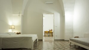 Un dormitorio con cama, mesita de noche, lámpara, silla y mesa con cesta.