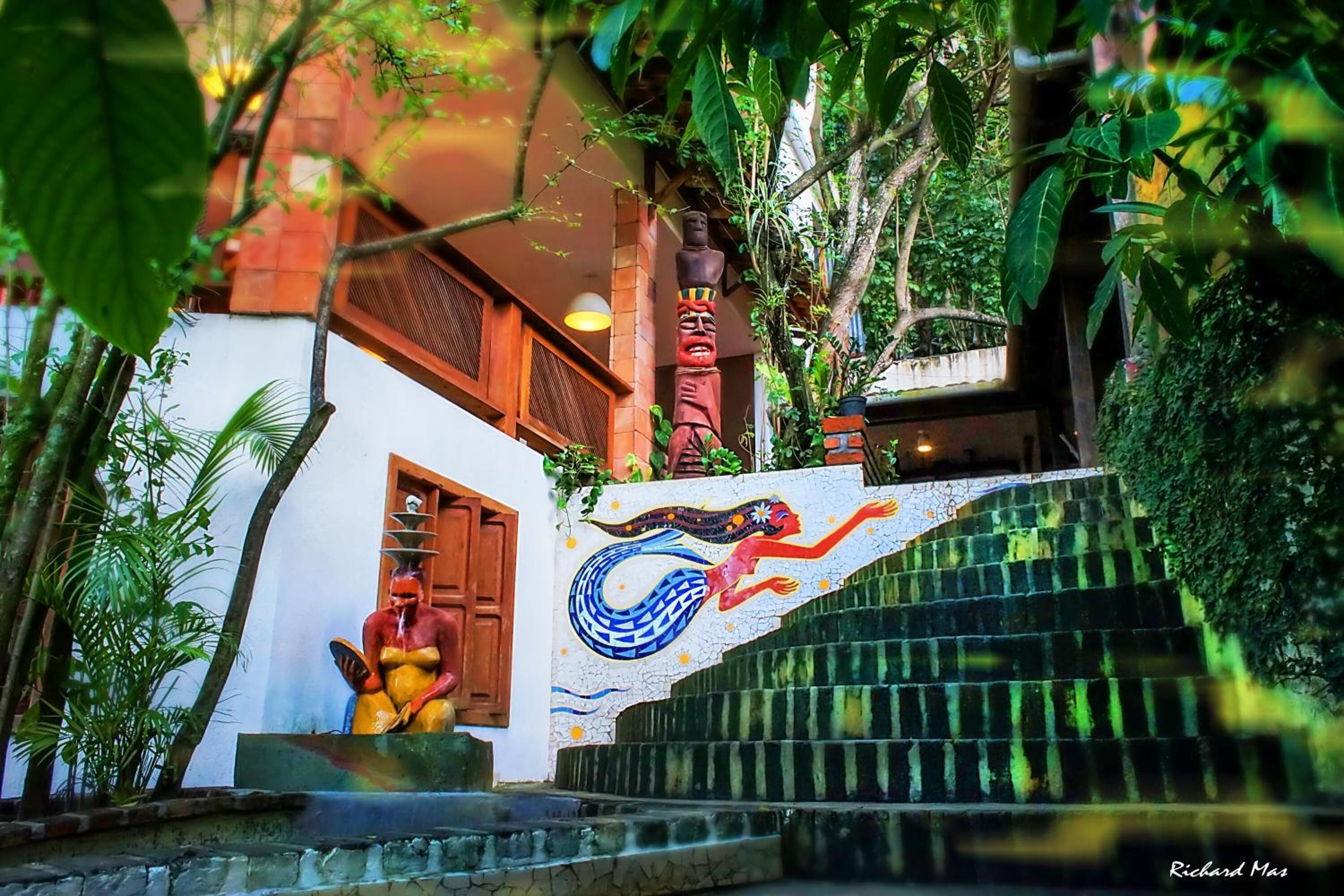 Uma escadaria com um mosaico de uma sereia, um tote de pole e uma estátua de mulher.