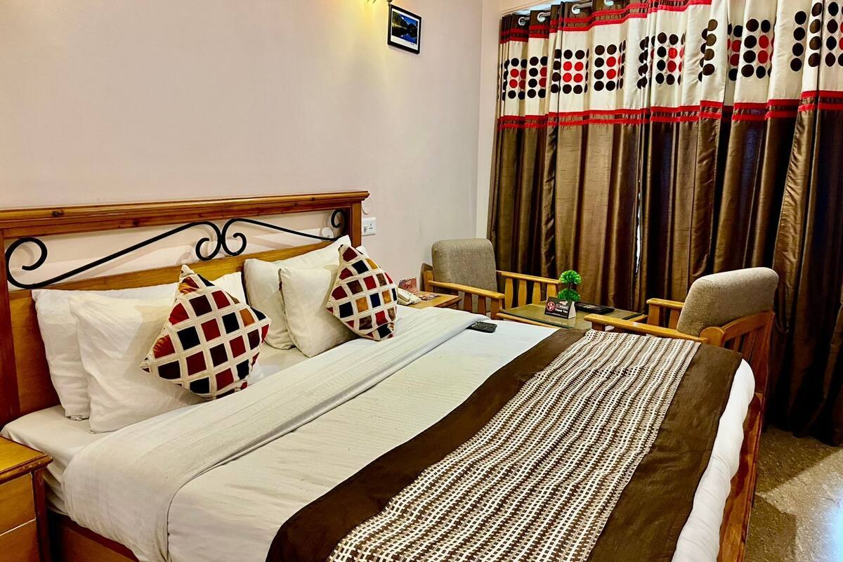 A hotel room with a bed, a desk, a chair, and curtains.