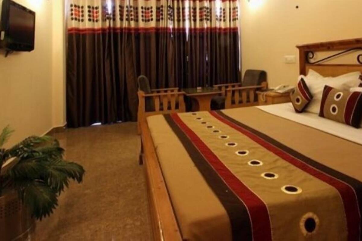 A hotel room with a bed, a desk, a chair, a television, and curtains.