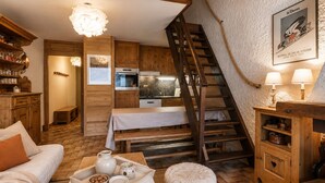 A cozy, rustic interior with wooden furniture, a dining area, a staircase, and a kitchen.