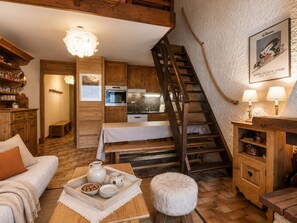 Un intérieur chaleureux et rustique, avec des meubles en bois, un coin repas, un escalier et une cuisine.