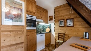A kitchen with wooden cabinets, a dishwasher, a stove, and a dining area with a table and chairs.
