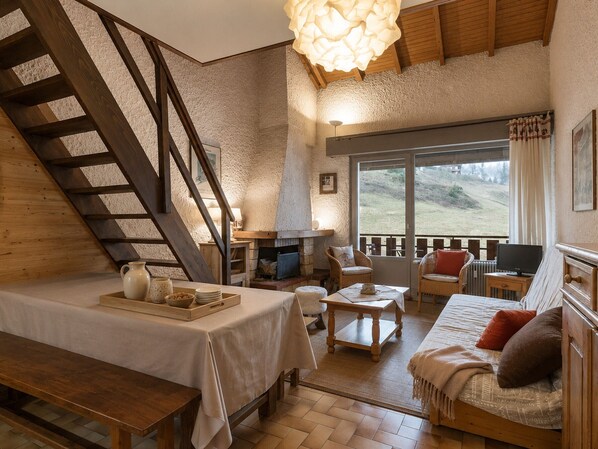 Una habitación acogedora con una cama, un sofá, una mesa y una chimenea.