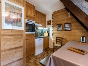 A kitchen with wooden cabinets, a dishwasher, a stove, and a dining area with a table and chairs.