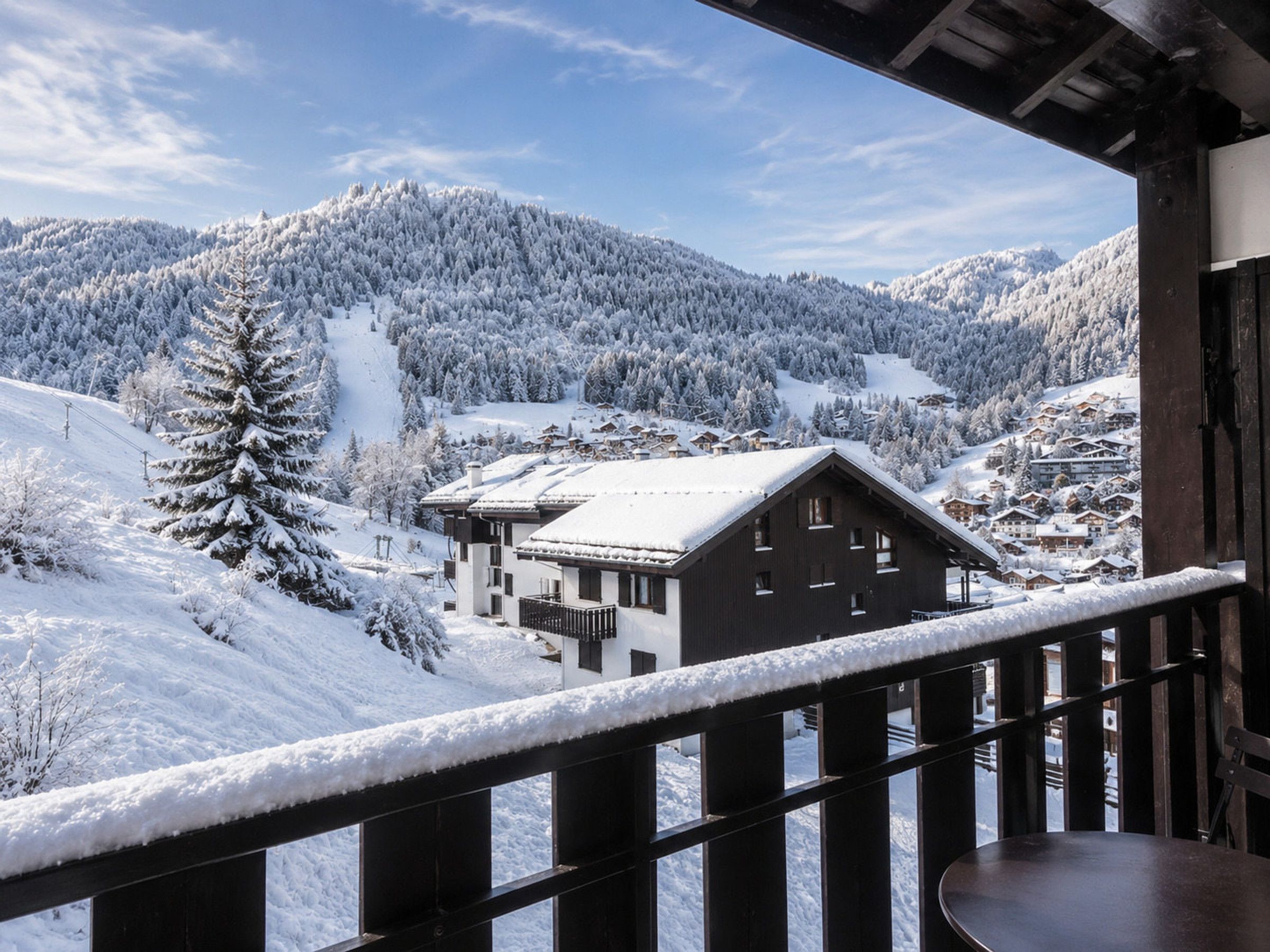 A wooden building with a balcony overlooking a snow-covered mountainous landscape.