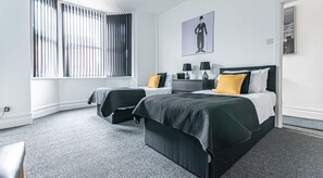 Habitación de hotel con dos camas, un ventanal con persianas y una vista panorámica de la ciudad.