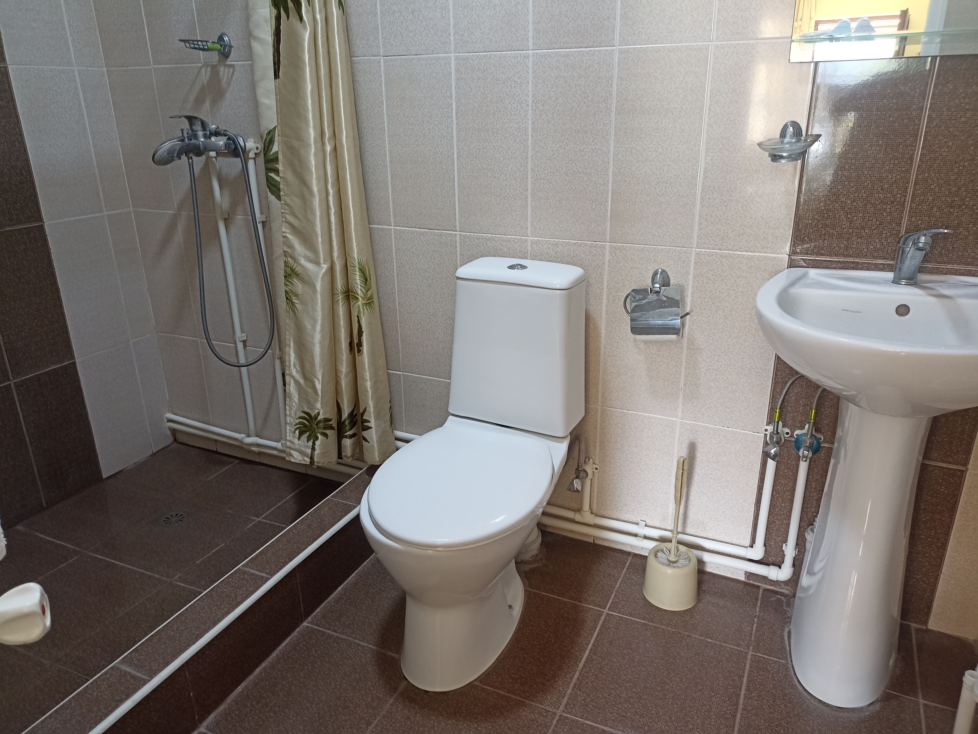 A bathroom with a toilet, shower, and sink.