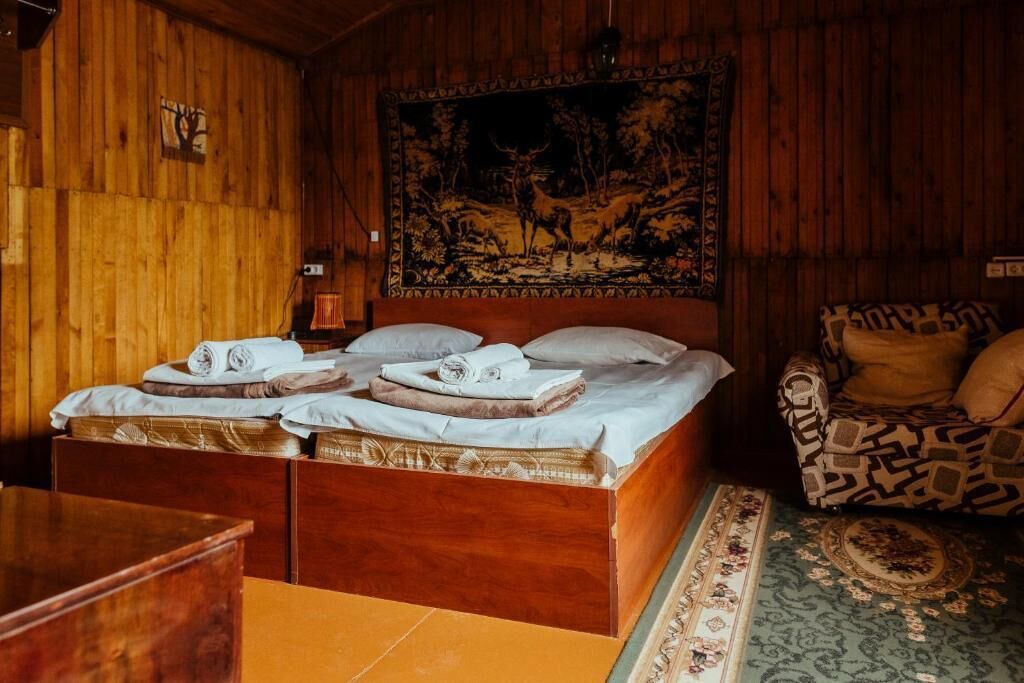 A wooden room with a bed, a patterned sofa, and a tapestry on the wall.