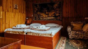 A wooden room with a bed, a patterned sofa, and a tapestry on the wall.