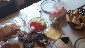 Una mesa de comedor dispuesta con diferentes alimentos, como pan, pasteles y salsas.