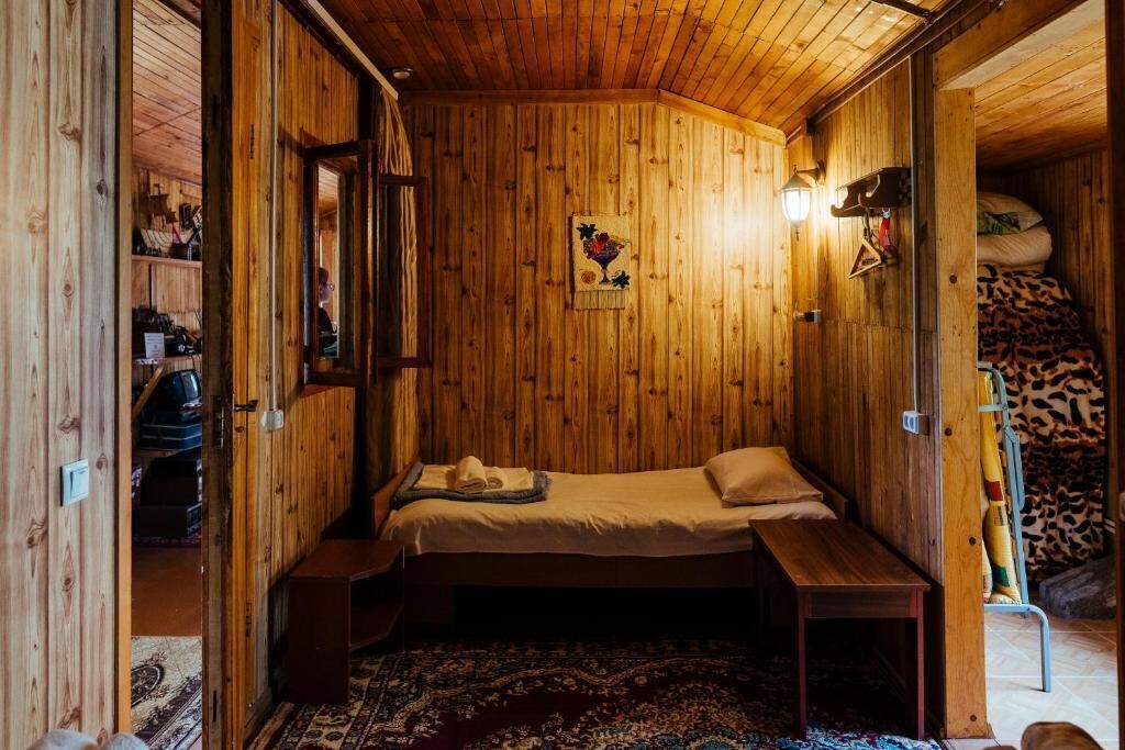 Ein Zimmer einer Holzhütte mit Bett, Bank und Teppich.