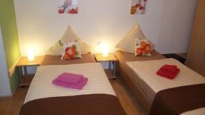Une chambre d’hôtel avec deux lits, chacun étant équipé d’un oreiller et d’une petite table de chevet.