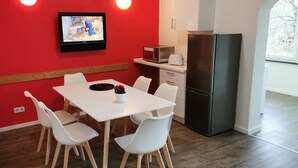 Une cuisine compacte avec une table et des chaises blanches, un four à micro-ondes, un grille-pain et un réfrigérateur.